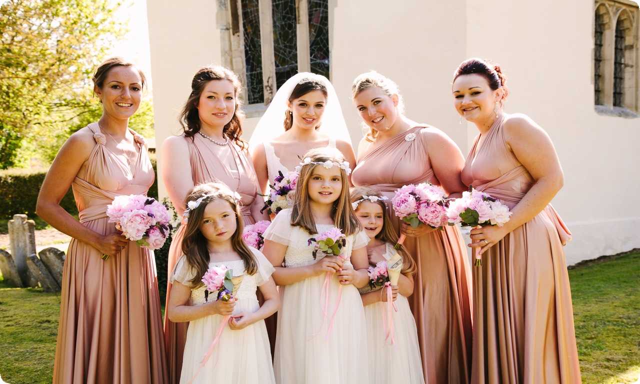 Дети-подружки невесты в Великобритании одеты в красивые платья и несут букеты цветов, подбрасывая лепестки на свадебной церемонии.