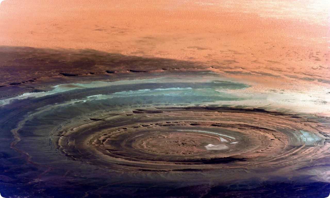 Око Сахары - это впечатляющий кратер, диаметром более 40 км, окруженный бескрайней пустыней, внутри которого находится красное озеро.